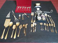 Overview of all silverware items neatly arranged on black fabric surface