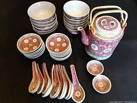 Overview of all set components including stacked bowls, dipping dishes, & spoons along with the tea pot.
