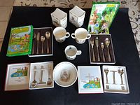Full lot display showing two boxed WMF children's utensil sets, two boxed WMF baby utensil sets, Royal Doulton Bunnykins cup, bowl, and two piggy banks.
