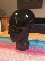 Side profile view of the vintage black glass head statue showing smooth glossy finish and detailed facial features.