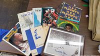 A selection of vintage magazines including Sports Illustrated, two New Yorker magazines, a 1976 NBA Playoffs magazine, and York Dumbbell exercise booklets displayed on a floor.