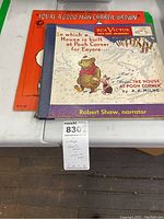 Two vinyl record albums placed side by side on a surface, "You're a Good Man Charlie Brown" with an orange cover and "House at Pooh Corner" narrated by Robert Shaw with an illustrated cover featuring Winnie the Pooh and Piglet.