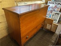 Front view of antique wooden blanket chest showing smooth top, front panel, and bottom drawer with two wooden knobs.