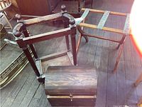 Lot showing all three pieces: wooden umbrella stand, wooden luggage rack with fabric straps, and small wooden chest with domed lid.