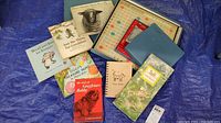 Photo showing all items in the lot arranged on a tarp including vintage children's books, Henry Moore's Sheep Sketchbook, Dog Lovers journal, and Scrabble game.