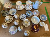 Overview photo showing 30 pieces of assorted vintage china including teacups, sugar bowls, serving plates, and a teapot with various floral and gold designs.