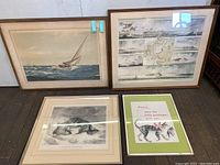 Photo showing four framed prints: a sailboat scene, a vintage map with ships, a detailed black and white animal etching, and a colorful cat print with text.