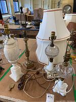 Four table lamps and three shades placed on a table, showing complete set and cords