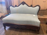 Full view of Victorian settee showing overall design, upholstery, and wooden frame.