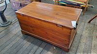 Front and side view of the wooden hope chest showing wood finish and handles on the sides.