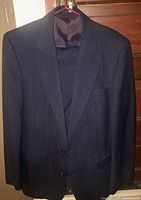 Dark pinstripe suit jacket hanging, visible pinstripe pattern and satin inner collar lining