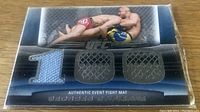 Front view of the fight mat relic card featuring George St Pierre with textile pieces embedded forming the number 100 and an in-action image of a grappling scene from UFC.