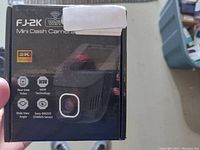 Front of black retail box showing FJ-2K Mini Dash Camera, 2K Ultra HD, WiFi, WDR, Wide Angle, Sony IMX335 STARVIS sensor branding