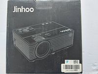 Two photos of the black box containing Jinhoo projector, featuring line drawing of the projector on front and top.
