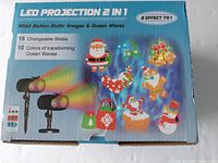 Photo showing packaging of LED Projection 2 in 1 projector with Christmas themed slides featuring Santa, reindeer, snowman, gifts and holiday symbols