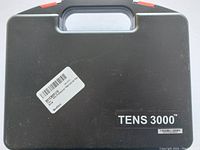 Closed black plastic carrying case labeled TENS 3000.