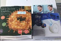 Photo of the LED String Lights box, Sky Lite Star Projector box, and two True Wireless Headset earbuds packages.