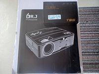 Photo of boxed Dr. J Professional video projector with boxed T95 TV Box on top.