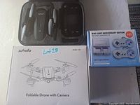 Photo showing Zuhafa foldable drone with camera in protective carrying case and Mini Game Anniversary Edition console box with 660 classic games.