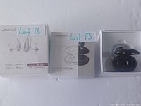 Three hearing devices displayed side by side on a white surface: boxed JH-D59 model hearing aids, boxed hearing amplifier, and black wireless ear hearing devices in charging case.
