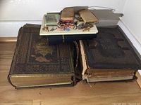 Three large worn Bibles stacked showing damaged bindings and ornate covers.