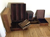 Photo showing all wooden boxes and drawer organizers arranged on wooden floor, various sizes and styles visible including dovetailed drawer organizers and boxes with lids.