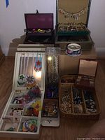 Front view showing multiple open boxes and trays filled with necklaces, bracelets and pins