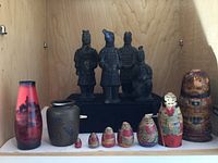 Wide view of entire lot showing nesting dolls, figurines, and both vases arranged on shelf