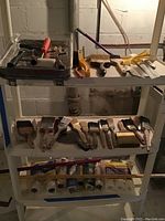 Shelf with assortment of paint brushes, some paint trays with a roller and paint roller covers on the lower shelves