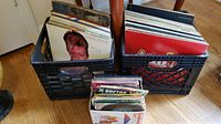 Two milk crates filled with vintage vinyl records, genres include show tunes, holiday, classical, and children's 45s, with cover of David Bowie's Aladdin Sane visible
