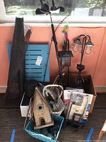 Lot showing the combined garden-related items including solar lights, birdhouse, baskets, and yard art pieces on a porch floor near a window.