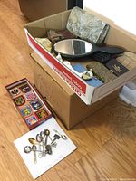 Box showing all items including spoons, coin purses, patches, hand mirror, miniature bottle, and beaded collar in assorted condition.