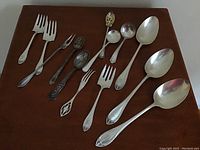Overall view of all forks, spoons and butter cutters arranged on wooden surface