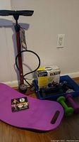 Photo of fitness equipment including Blackburn Air Tower 2 air pump, Simply Fit Board in purple color, boxed fitness ball, green hand weights, hand grips, Apollo stopwatch, and small fitness accessories in blue tray.