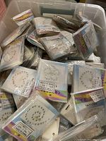 Multiple sealed packs of crystal temporary tattoos inside a plastic container. Each pack shows crystal designs formed by small rhinestone-like elements.