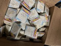 Box filled with multiple crystal self-adhesive temporary tattoo packs, showing designs and labels