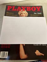 Cover of 1997 January Playboy magazine partially obscured by white paper, showing Marilyn Monroe and text about Holiday Anniversary issue.