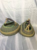 Two green patterned woven baskets with sturdy handles on a light gray fabric background.
