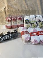 Packages of socks showing children's pink and white socks, white sports socks with pink toes, black socks, and character print socks.