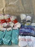 Photo showing multiple packages of socks including turquoise, white with pink toes and heels, novelty themed (Harry Potter, Funny), and a 6-pack of ladies' short socks.