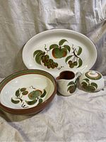 Full set of Stangl ceramic serveware including oval platter, round bowl, pitcher, and covered sugar bowl displayed together on a cloth background.