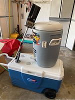 Overall view showing the Coleman cooler at the bottom, MaxCold beverage cooler on top, and metal detector leaning against them.