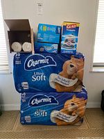 Photo showing two packs of Charmin Ultra Soft toilet paper jumbo rolls stacked with boxes of Ziploc bags and a box of Glad ForceFlex Plus trash bags on top.