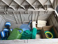 Large plastic storage container with assorted pool accessories including foam noodles, green watering can, straps, and plastic components.