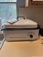 Nesco 18 quart roaster oven closed with lid and control knob visible on the front.
