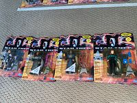 Four Star Trek: The Next Generation action figures in original Playmates packaging, arranged in a row on carpet.