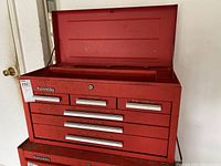Front angled view of the red metal tool box with all drawers closed except top lid open, showing red paint and Kennedy branding.