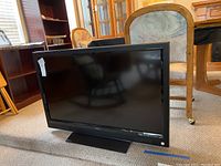 Front view of the Vizio flat screen TV showing the screen, base stand and Vizio logo on the front speaker grille.
