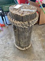 Front view of cylindrical yard ornament showing wood grain texture and rope detail