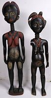 Front view of two wooden African sculptures, one larger and one smaller both with painted details